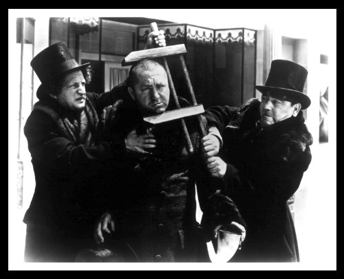 The Three Stooges - Moe Howard, Larry Fine, and Curly Howard - in a publicity still, with Curly's head in a vice.