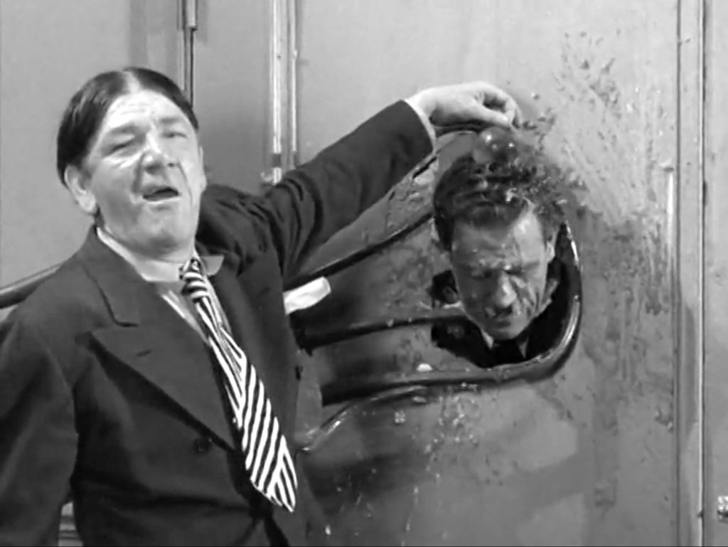 Step right up …
Shemp has locked Slipp's head through the hole of the dressing room door with a chair