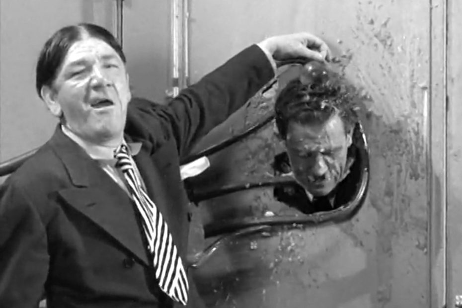 Step right up … Shemp has locked Slipp's head through the hole of the dressing room door with a chair