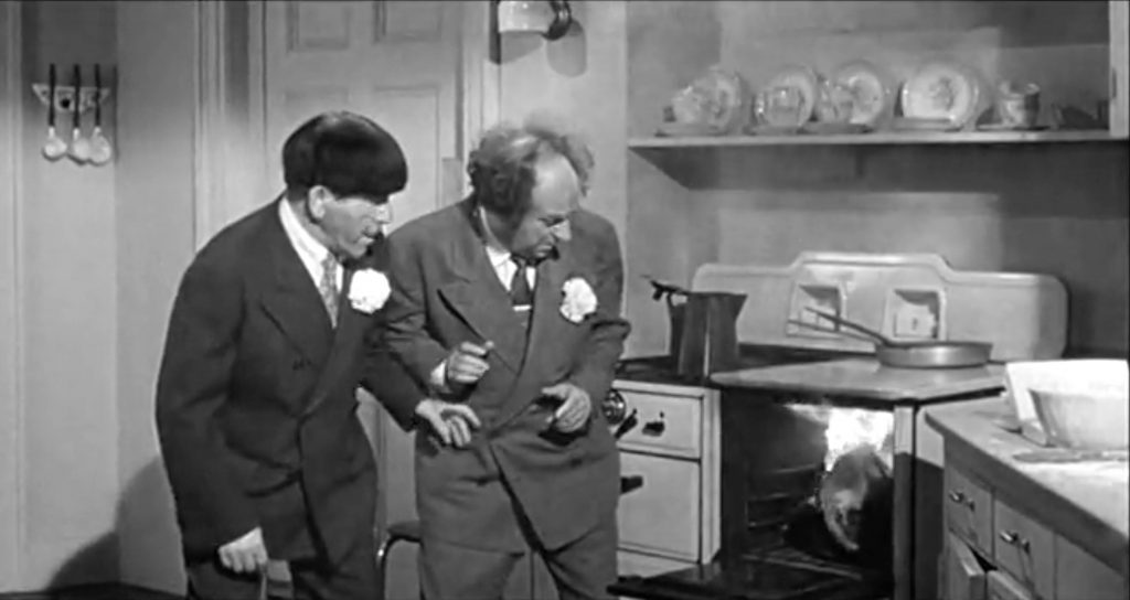 Moe and Larry look on as the turpentine turkey catches fire in the oven in "Husbands Beware"
